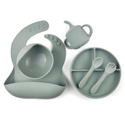 Sage green silicone baby feeding set including a divided suction plate, bowl, bib with food catcher, sippy cup, spoon, and fork. Perfect for weaning and toddler feeding
